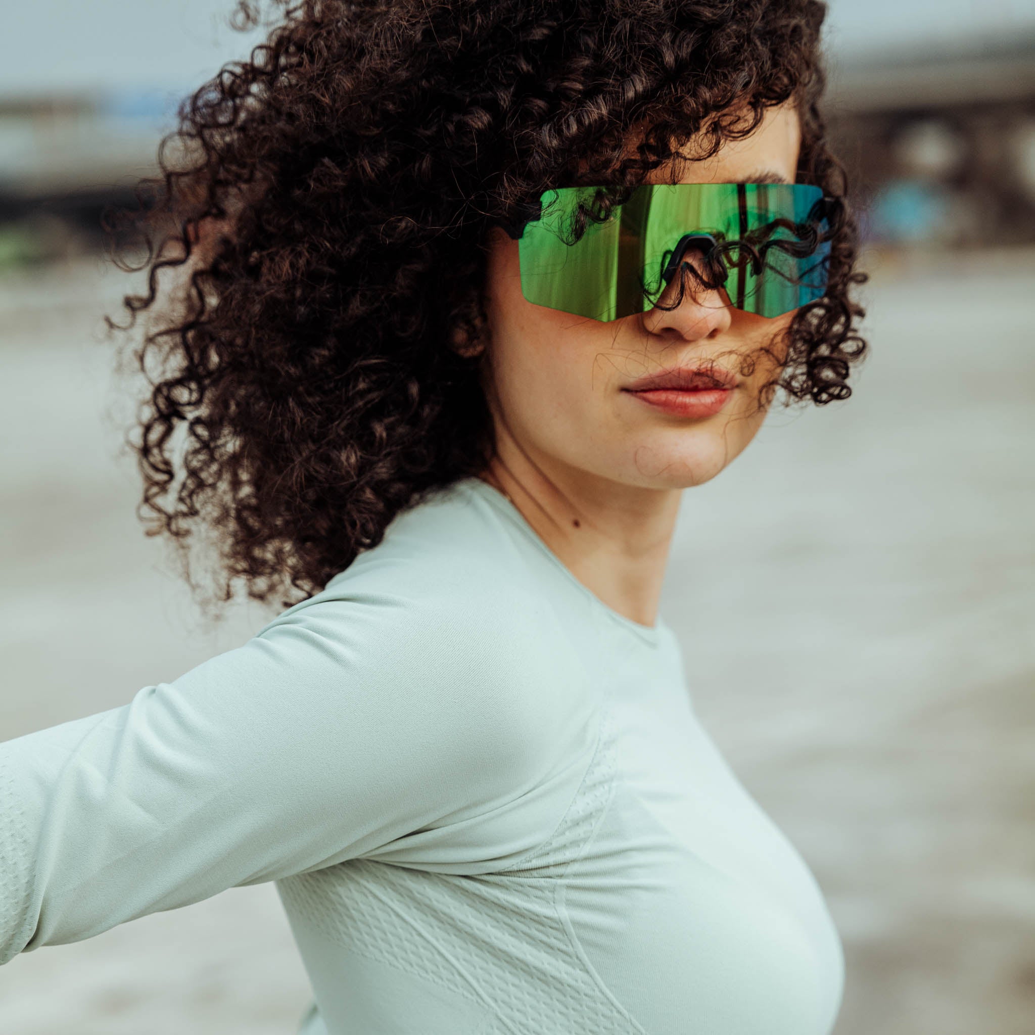 Young athlete with curly hair and large green sports sunglasses